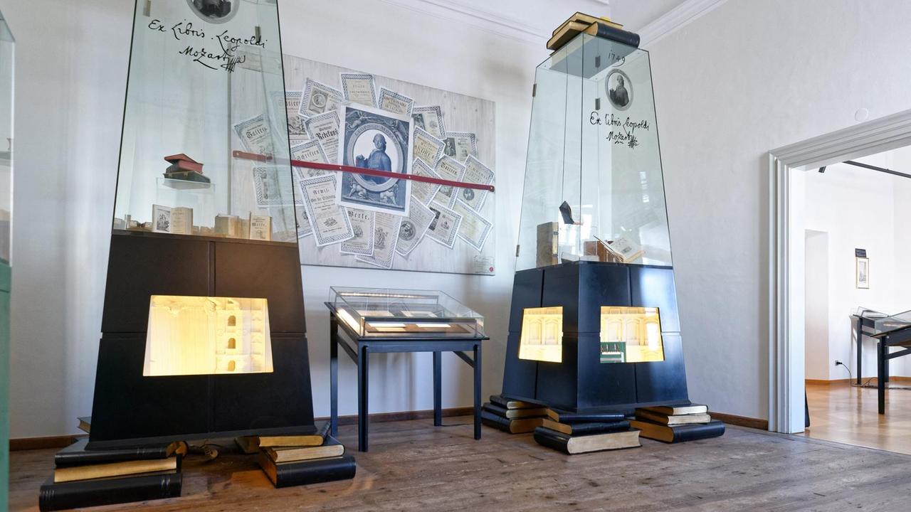 Das Bild zeigt Glasvitrinen mit Büchern und ein Bild, auf dem Leopold Mozart und einige Urkunden abgebildet sind