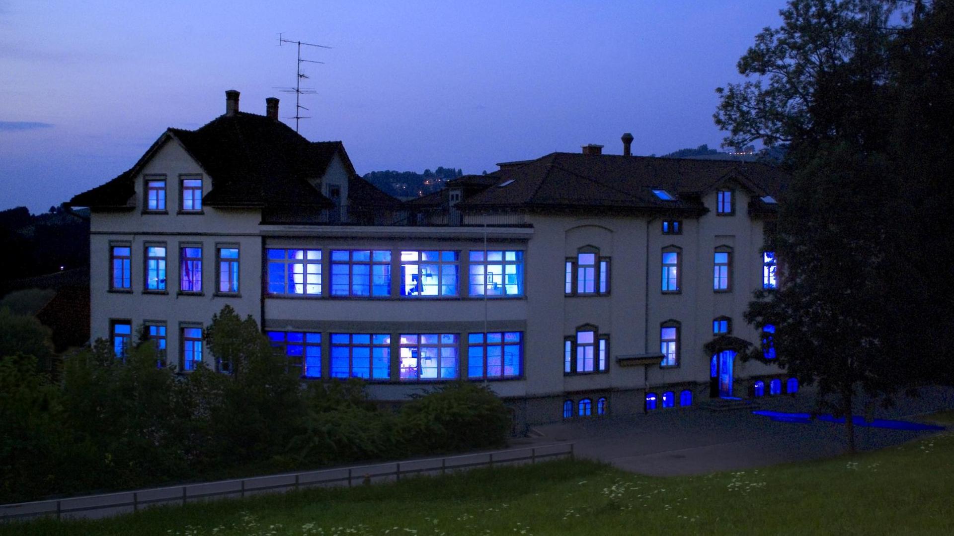 Ein ehemaliges Krankenhausgebäude ist von innen blau erleuchtet