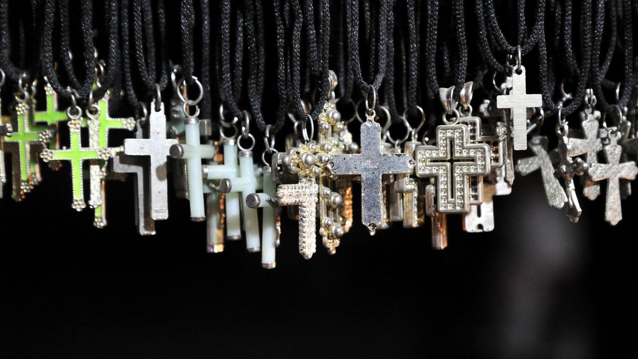 Kruzifixe als Kettenanhänger an einem Verkaufsstand mit christlichen Artikeln.