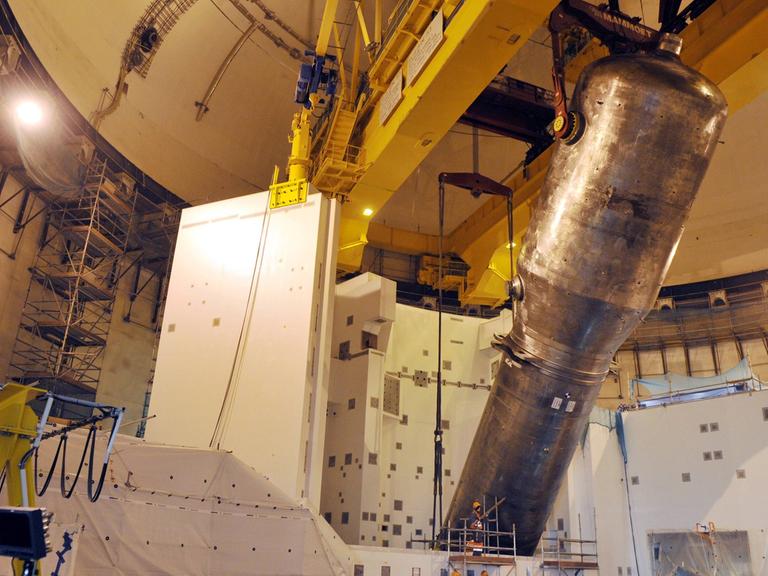 Im Inneren von Olkiluoto 3 wird ein Metallbehälter von einer großen Maschine angehoben.