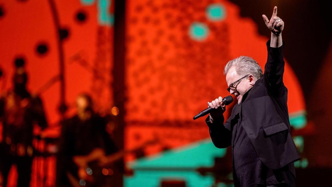 Herbert Grönemeyer steht in einer Rock-Pose auf der rot erleuchteten Bühne