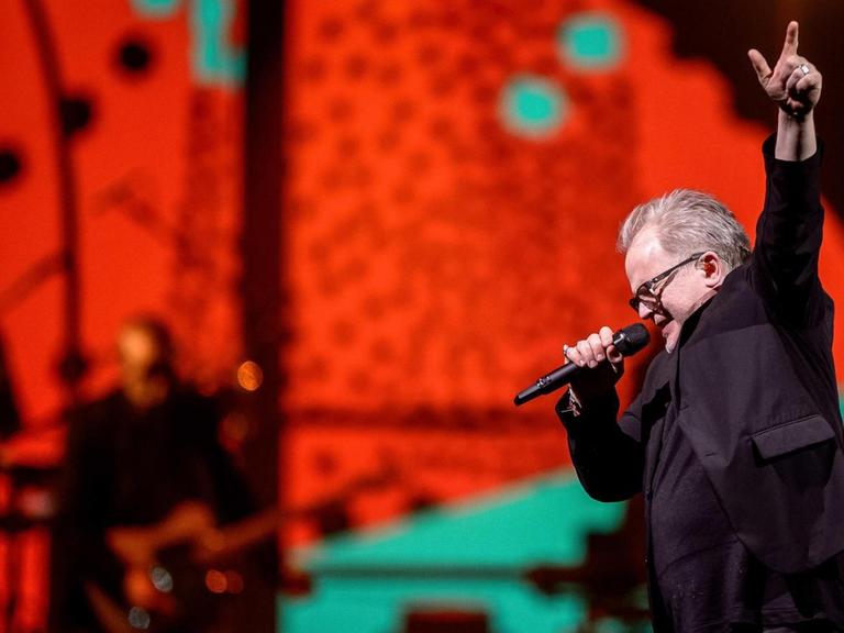 Herbert Grönemeyer steht in einer Rock-Pose auf der rot erleuchteten Bühne