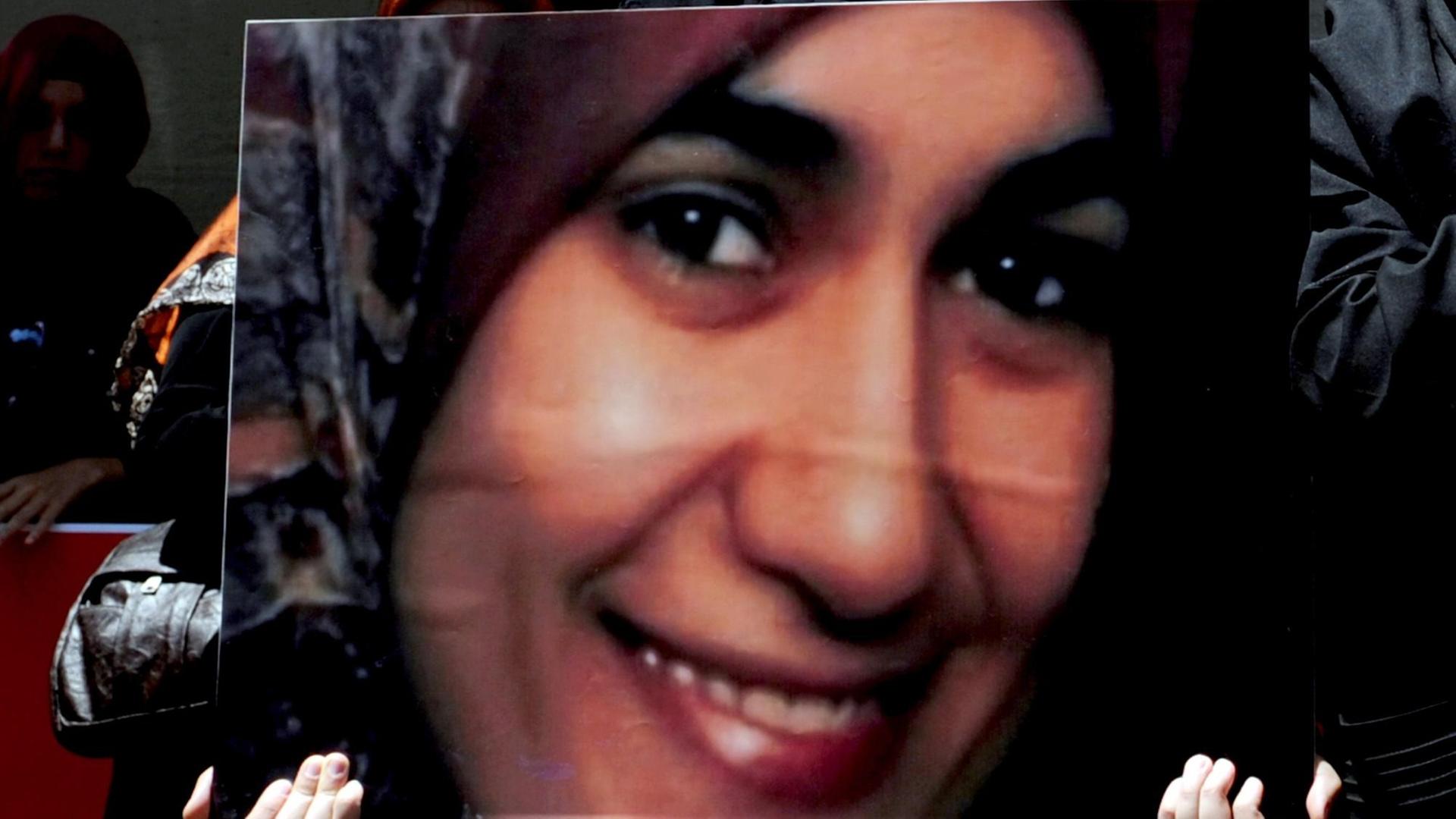Jemand hält ein Poster der ermordeten Muslimin Marwa El-Sherbini in die Höhe.