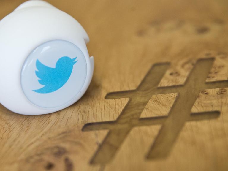 Ein Gadget mit dem Logo des Kurznachrichtendienstes Twitter Deutschland auf einem Besprechungstisch mit eingraviertem Zeichen Hashtag.
