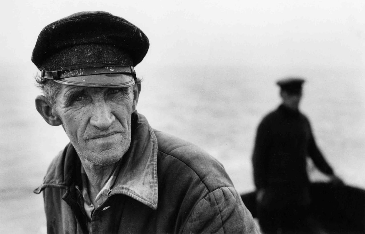 Das Schwarz-Weiß-Foto zeigt einen älteren Mann mit einer Kappe.