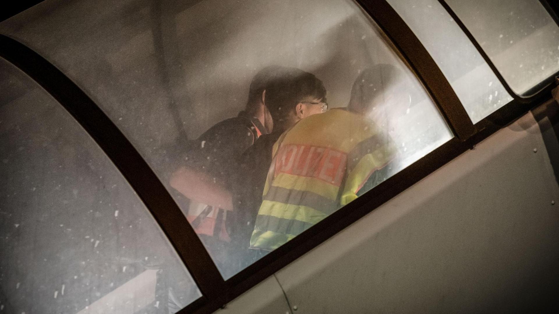 Polizeibeamte begleiten einen Afghanen auf dem Flughafen Leipzig-Halle in ein Flugzeug.