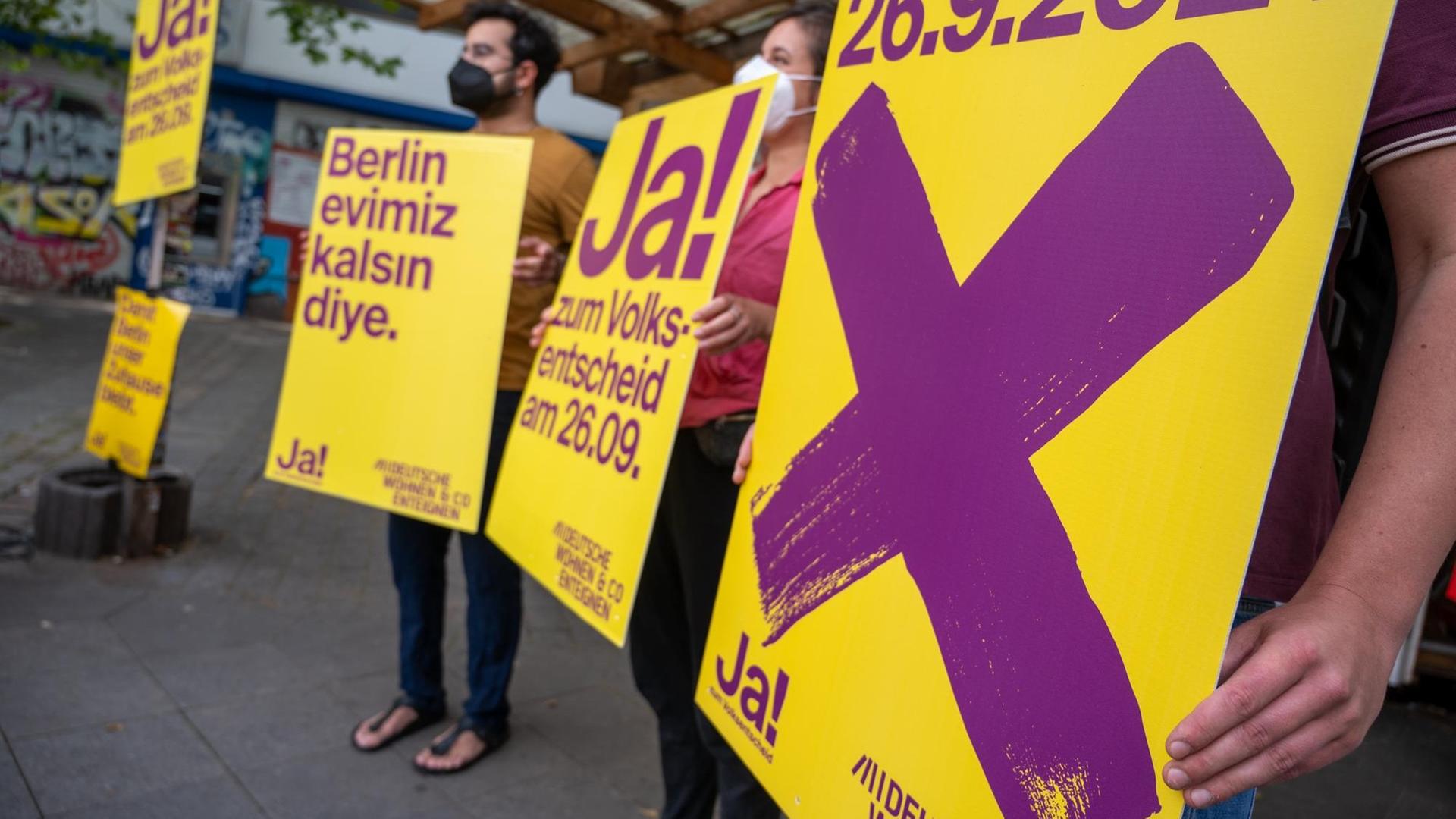 Anhänger der Kampagne "Deutsche Wohnen und Co. enteignen" halten bei einer Veranstaltung Plakate der Kampagne, auf denen für den dazugehörigen Volksentscheid in Berlin geworben wird.
