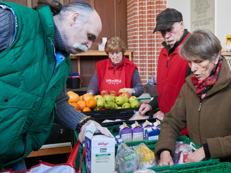 Ehrenamtliche Helfer von "Laib und Seele" sind bei der Essensausgabe von bedürftigen Menschen in einem Vorraum der Evangelischen Advent-Zachäus Kirche beschäftigt.