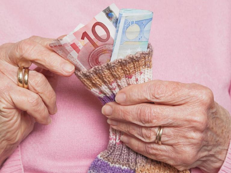 Eine ältere Dame zählt ihr Geld.