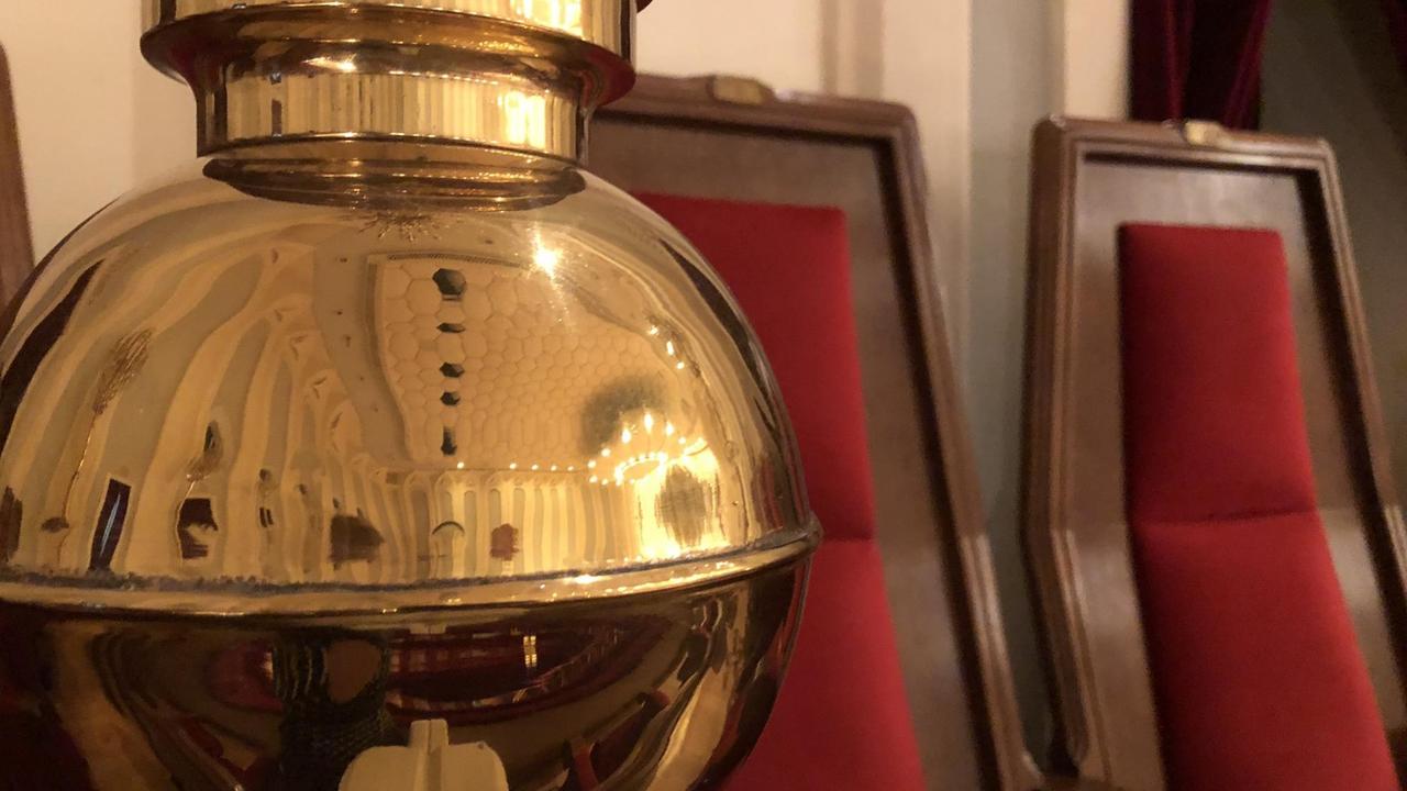 In einer goldenen Schmuckkugel kann man den Saal gespiegelt sehen, im Hintergrund rote Samtsitze