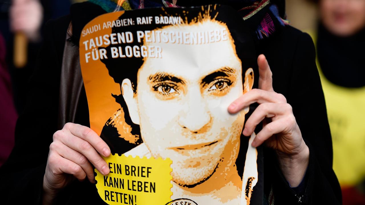 Eine Aktivistin von Amnesty International hält ein Plakat mit Raif Badawi hoch und fordert dessen Freilassung bzw. das Ende der Prügelstrafe vor der saudi-arabischen Botschaft in Deutschland am 29. Januar 2015.
