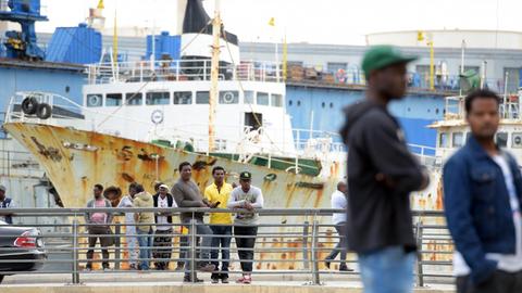 Flüchlinge beobachten am 30.04.2015 am Rande des Geländes eines offenen Flüchtlingszentrum in Marsa (Malta) das Geschehen. Das Flüchtlingszentrum liegt am Rande eines Schiffsfriedhofs.