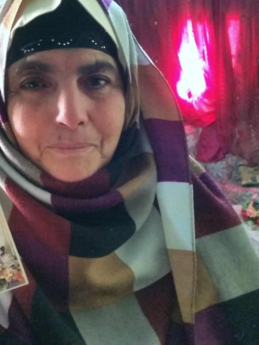 Eine Mutter in Tunesien zeigt das Bild ihres Sohnes in die Kamera. Sie steht im Wohnzimmer.