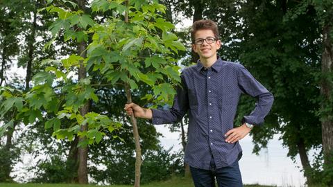 Felix Finkbeiner, der Initiator der Umweltschutzorganisation "Plant for the Planet", posiert in Uffing am Staffelsee neben einem jungen Baum.