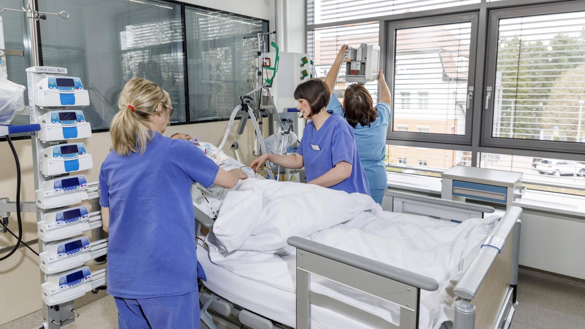 Drei Pflegerinnen am Bett eines Patienten