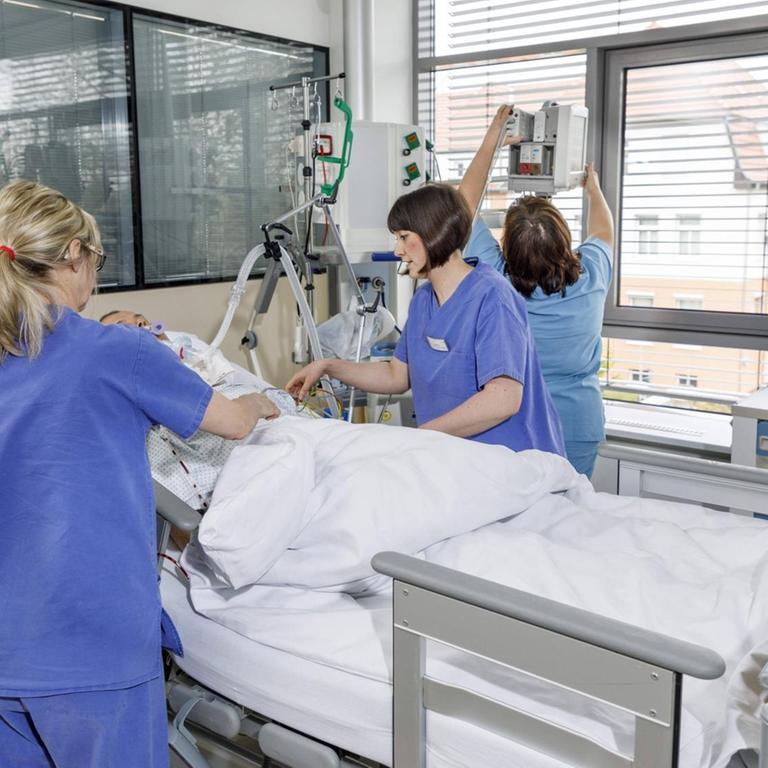 Drei Pflegerinnen am Bett eines Patienten