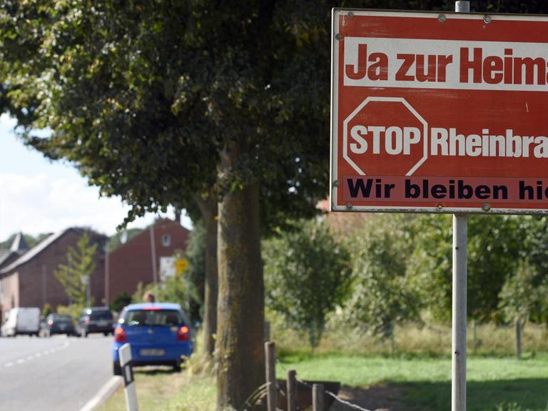 Jahrelang stand dieses Schild am Ortseingang von Keyenberg, bald wird es den Kohlebaggern weichen, so wie die Kirche und Häuser im Hintergrund