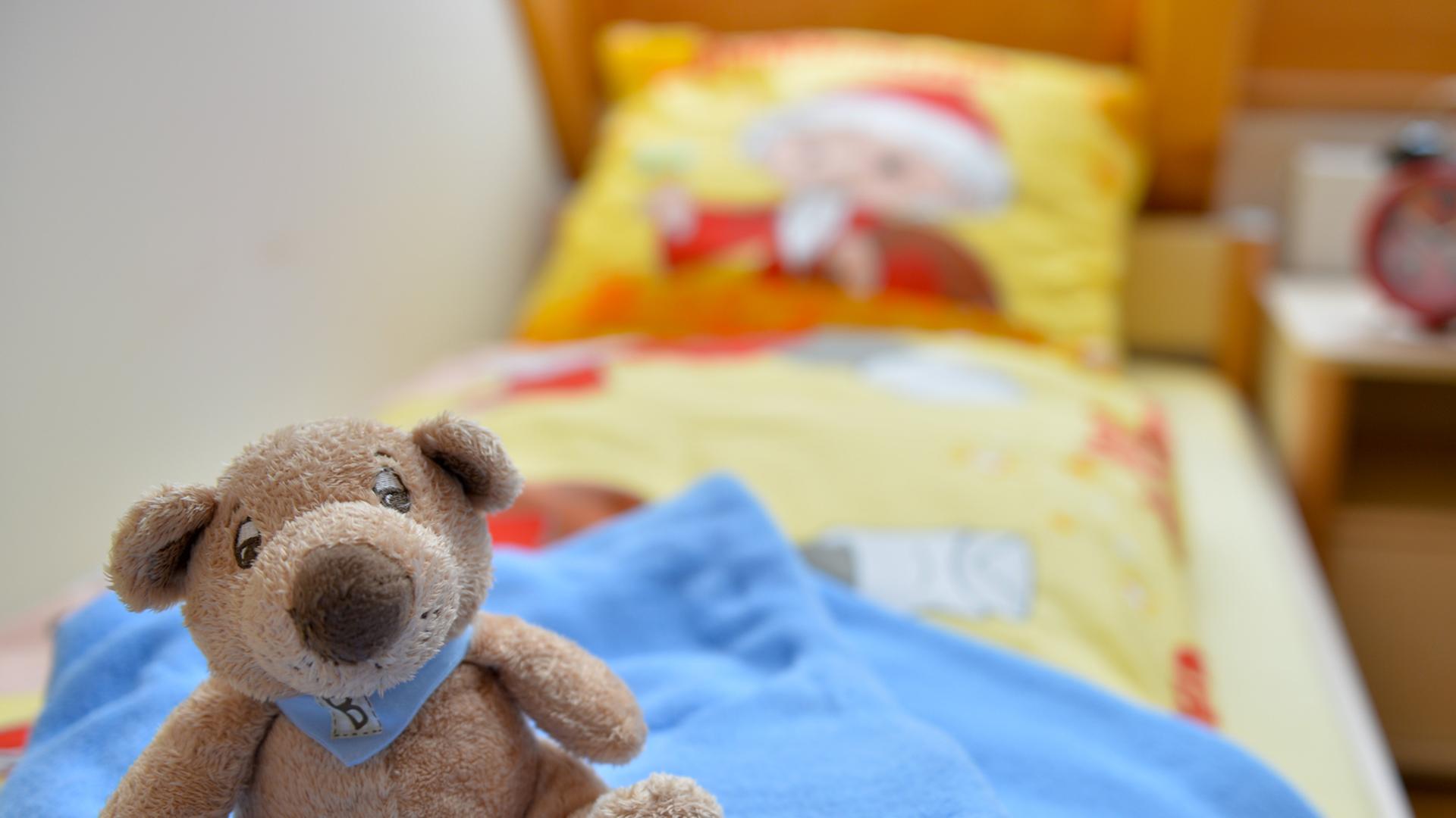 Ein Stofftier sitzt in einem Kinderzimmer auf einem Bett.