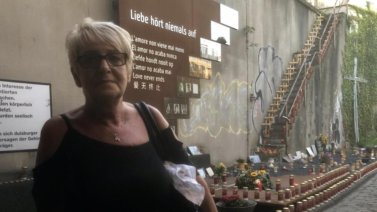 Gabi Müller steht vor der Gedenkplakette am Unglücksort der Loveparade-Katastrophe in Duisburg.