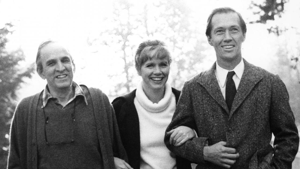 Der schwedische Regisseur Ingmar Bergman lacht mit den beiden Hauptdarstellern Liv Ullmann und David Carradine seines neuen Films "Das Schlangenei", aufgenommen 1977 in München am Rande der Dreharbeiten.