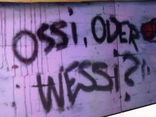 Ossi oder Wessi, fragt ein Graffito an der Wand. Auch mehr als 30 Jahre nach der Wiedervereinigung existieren diese Kategorien.