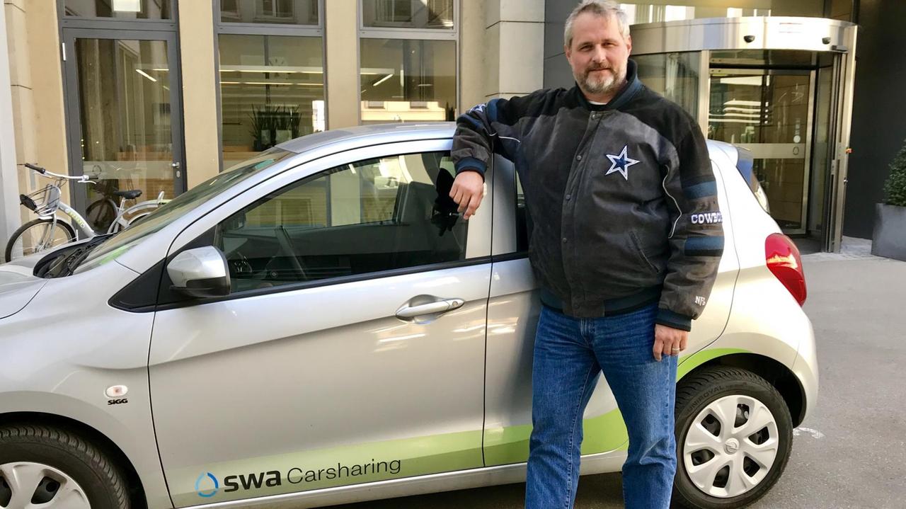 Alexander Görbing mit einem Wagen, den die Augsburger Stadtwerke als Carsharing anbieten. 