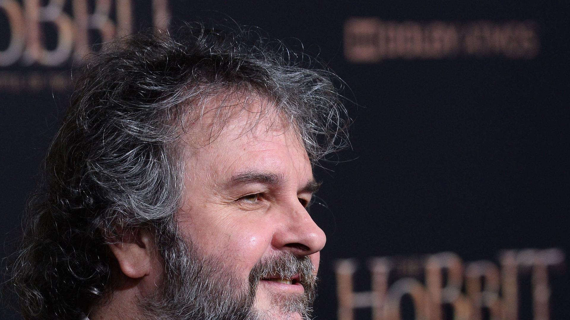 Regisseur Peter Jackson steht vor einem Filmplakat mit der Aufschrift Hobbit