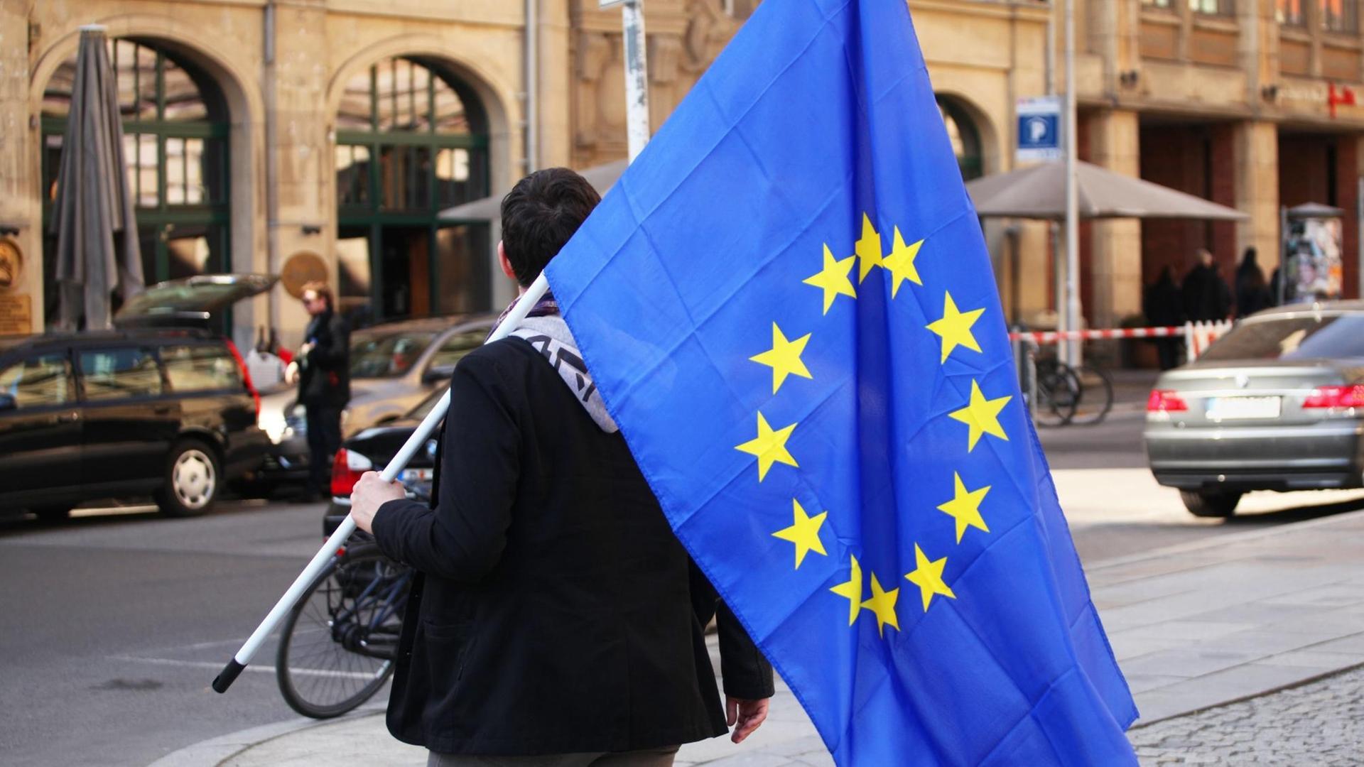 Ein junger Mann trägt eine Europafahne nach einem "Pulse of Europe" Event auf dem Gendarmenmarkt in Berlin im Bezirk Mitte am 26.03.2017. Mehrere Tausend Menschen demonstrierten an dem Tag auf dem Gendarmenmarkt für ein friedliches, geeintes und grenzfreies Europa.
