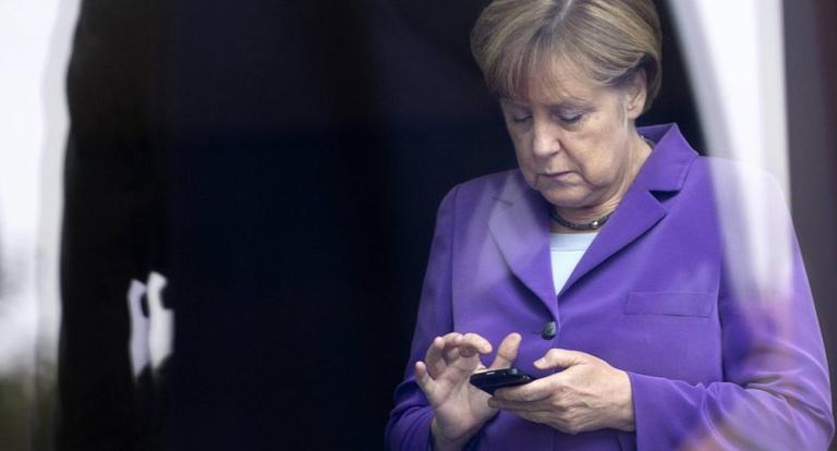 Angela Merkel schaut auf ihr Handy.