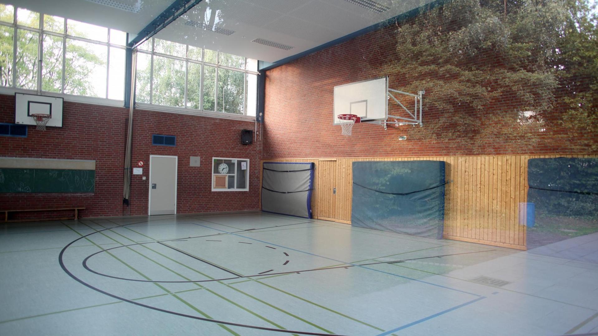 Der Blick durch eine Fensterscheibe zeigt eine leere Turnhalle.
