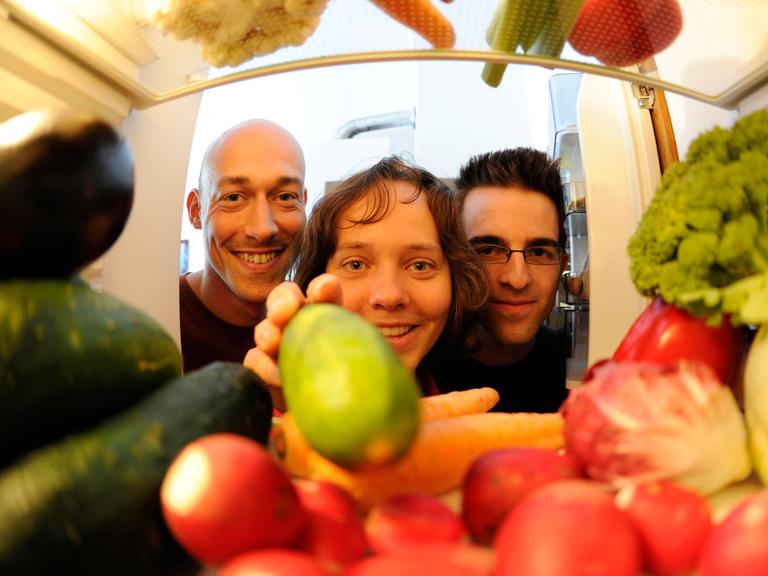 Die sich vegan ernährenden Robert Kresse (l), Silke Bott (M) und Robert Elzer (r) blicken in ihrer Wohngemeinschaft in Karlsruhe in den mit Gemüse gefüllten Kühlschrank (Foto vom 04.08.2010).