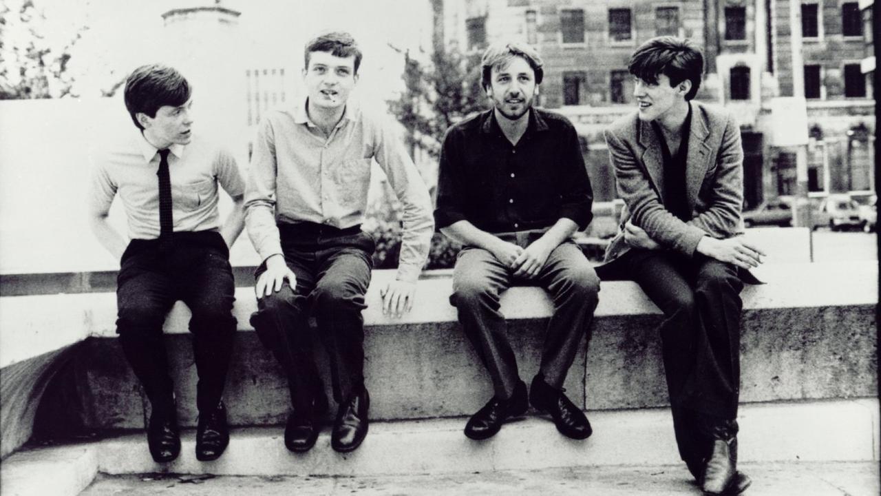 Die Bandmitglieder von Joy Division vereint auf eine Zigarette auf der Bank. 