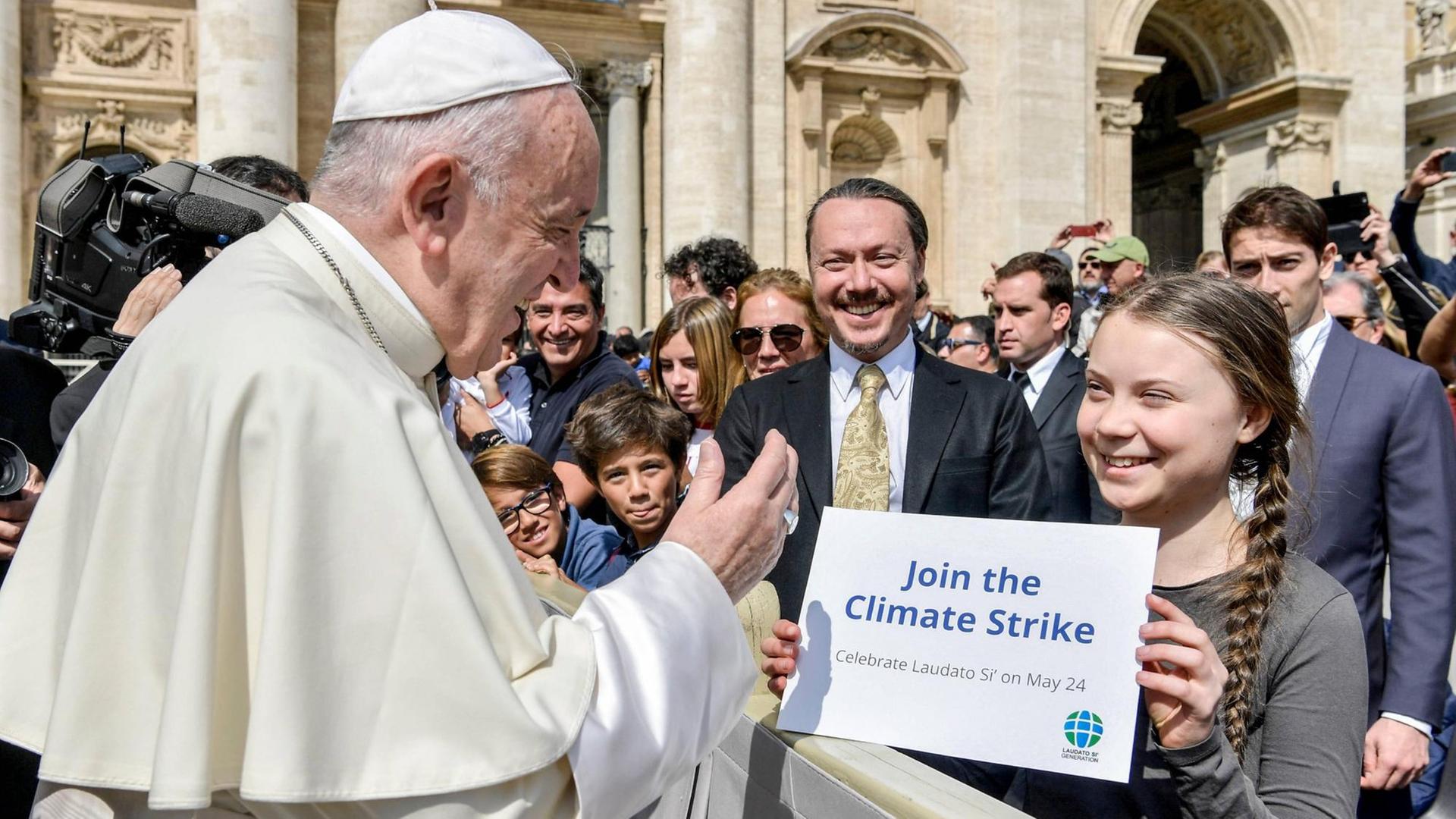 Die schwedische Klimaaktivistin Greta Thunberg steht bei der Generalaudienz des Papstes am 17.4. 2019 in der ersten Reihe und hält Franziskus ein Schild mit der Aufschrift "Join the Climate Strike" entgegen.