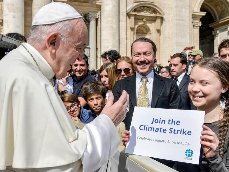 Die schwedische Klimaaktivistin Greta Thunberg steht bei der Generalaudienz des Papstes am 17.4. 2019 in der ersten Reihe und hält Franziskus ein Schild mit der Aufschrift "Join the Climate Strike" entgegen.