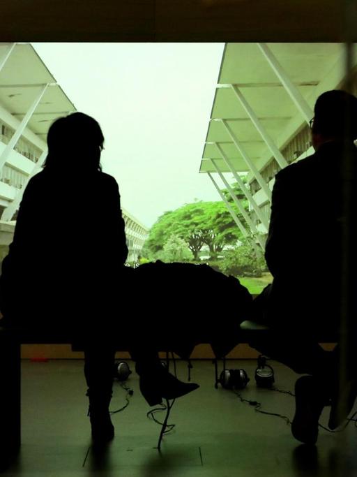 Die Ausstellung "Bauhaus Imaginista" im Berliner Haus der Kulturen der Welt. Zwei Besucher sitzen vor einer Leinwand oder einem Bildschirm und schauen sich eine Installation an.