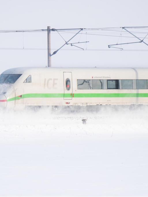 Ein ICE der Deutschen Bahn fährt über die ICE-Trasse Hannover - Berlin und wirbelt Schnee auf.