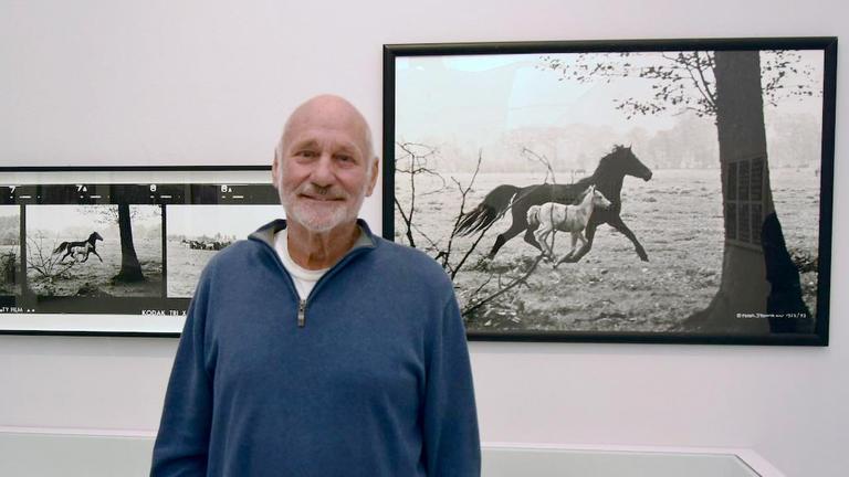 Porträt des Fotografen Peter Thomann vor seinem berühmten schwarz/weiss Foto "Stute mit Fohlen".