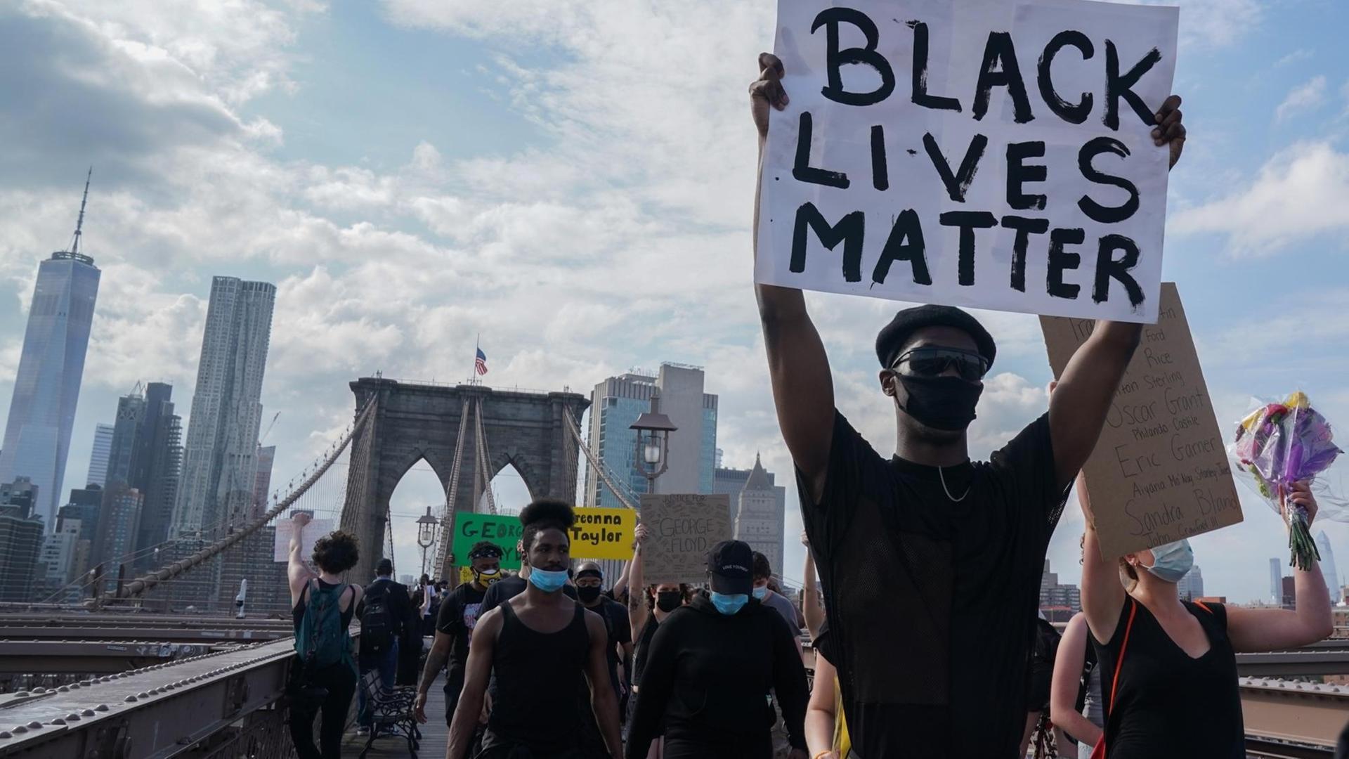 Protesters hold up signs as they demonstrate in outrage over the death of George Floyd by a Minneapolis police officer at a rally in lower Manhattan in New York, United States.