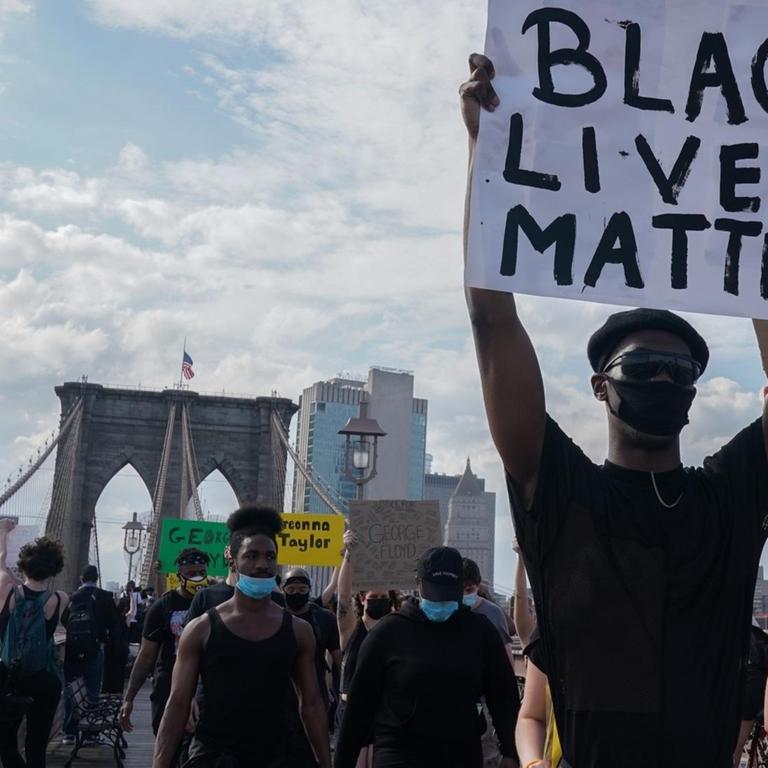 Protesters hold up signs as they demonstrate in outrage over the death of George Floyd by a Minneapolis police officer at a rally in lower Manhattan in New York, United States.