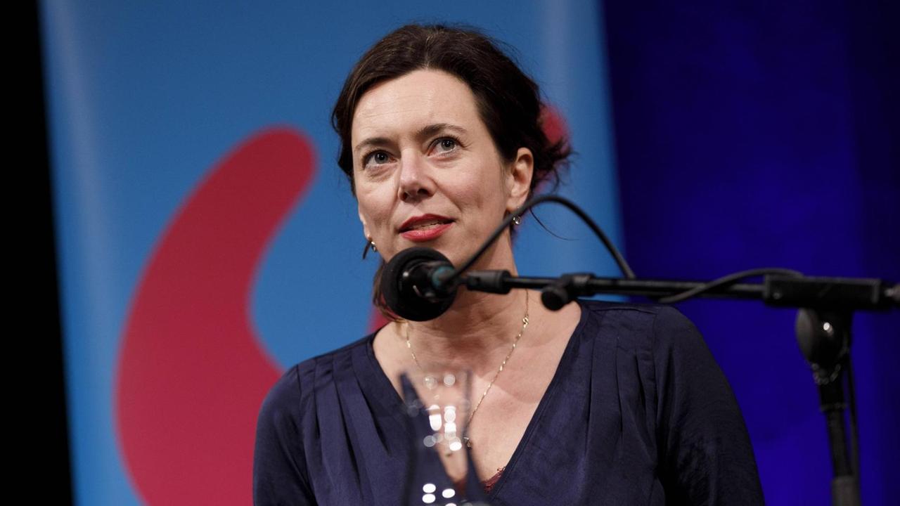 Eva Menasse sitzt vor einem Mikrofon während der lit.COLOGNE 2019 und blickt ins Publikum. Eva Menasse sitzt vor einem Mikrofon während der lit.COLOGNE 2019 und blickt ins Publikum.
