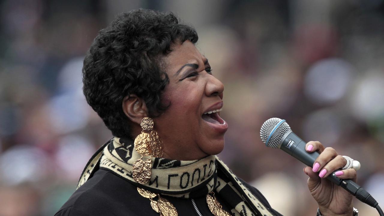 Aretha Franklin hält bei einem Auftritt singend ein Mikrofon in der Hand