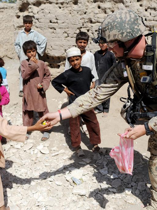 Bundeswehrsoldaten verteilen im Distrikt von Charah Darreh nahe Kundus während einer Patroillle Bonbons an Kinder. Die Soldaten suchten nach versteckten Sprengfallen und deren Urhebern. (August 2011)