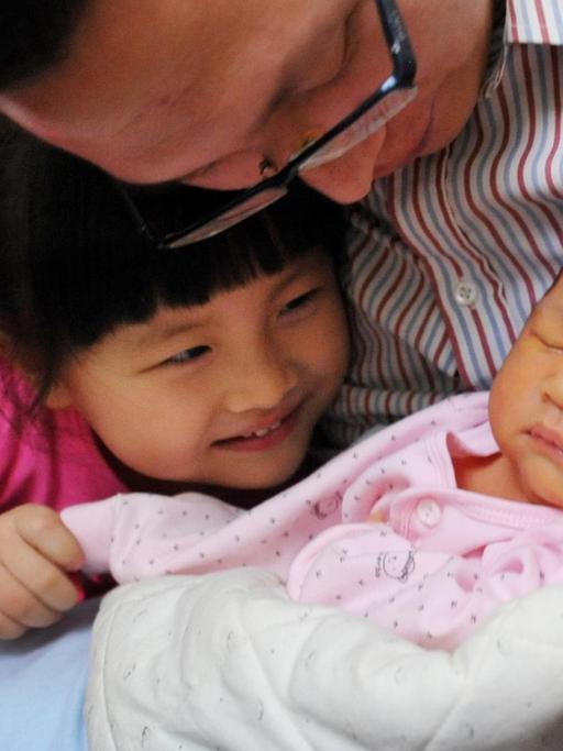 Ein chinesischer Vater mit einem Baby und einem Kleinkind.