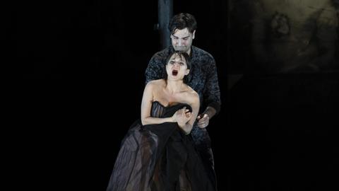 Eine Probenaufnahme von Berry Koskys Inszenierung von Giacomo Puccinis "La Bohème" zeigt im Bühnendunkel die Sängerin der Rolle der Mimi in üppigen Kleid , dramatisch singend in den Armen eines bleichen Rodolfo