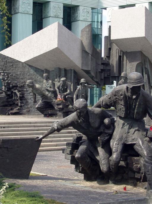 Das Bild zeigt das Denkmal für den Warschauer Aufstand in Warschau, im Vordergrund ein Blumenbeet.