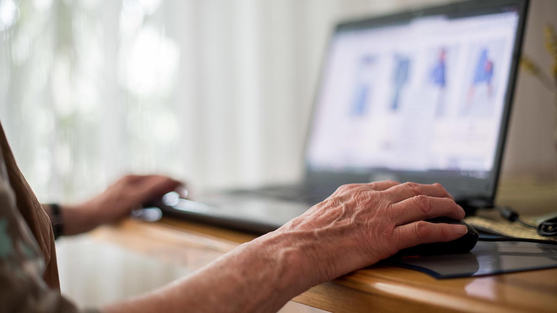 Eine Seniorin sitzt an ihrem Laptop
