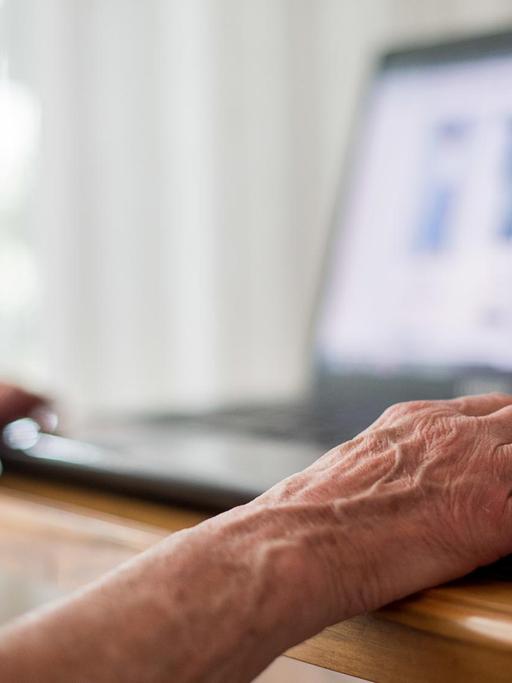 Eine Seniorin sitzt an ihrem Laptop