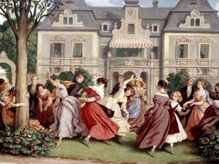 Festlich gekleidete, junge Menschen tanzen wirbelnd vor einer Schlosskulisse auf einem Rasen zwischen blühenden Büschen.