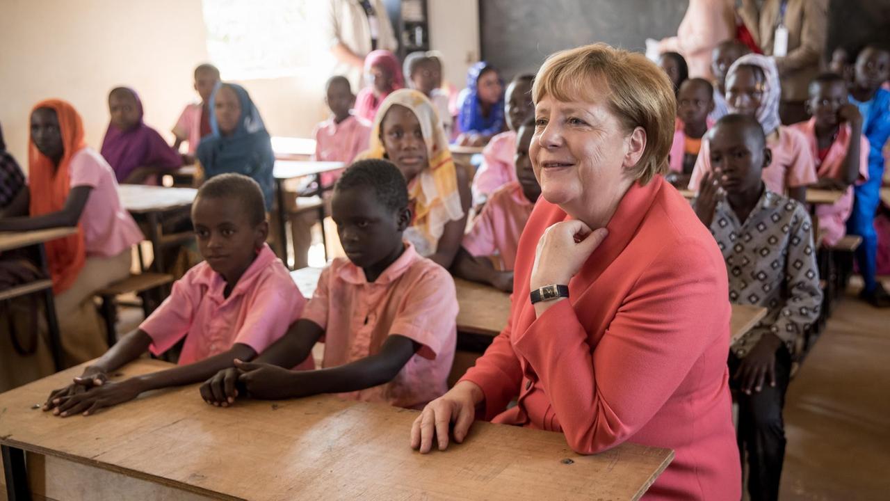 Bundeskanzlerin Merkel sitzt während ihrer Afrikareise in Niamey mit Schülern in auf einer Klassenbank. 