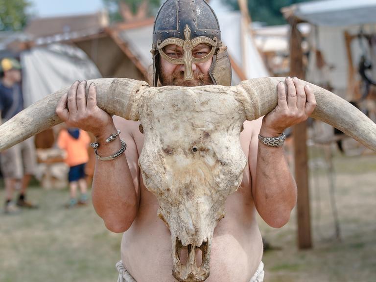 Ein Mann posiert als Wikinger mit einem Rinderschädel beim Winkingerfest in Schleswig (Schleswig-Holstein).